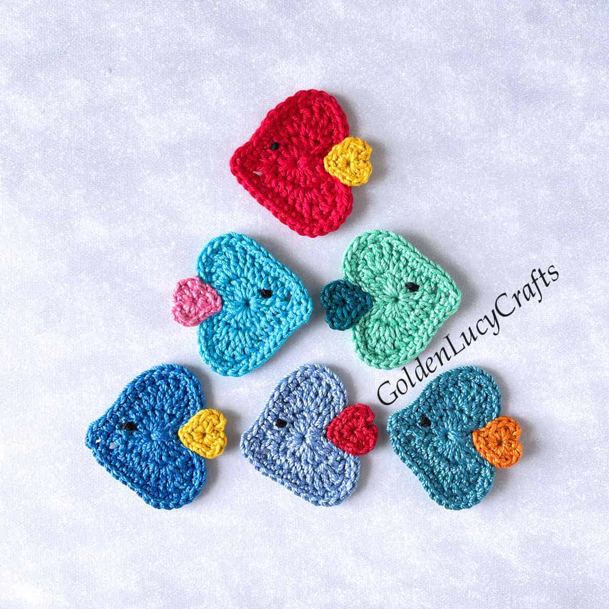 Crocheted fish appliques arranged into a triangular shape.