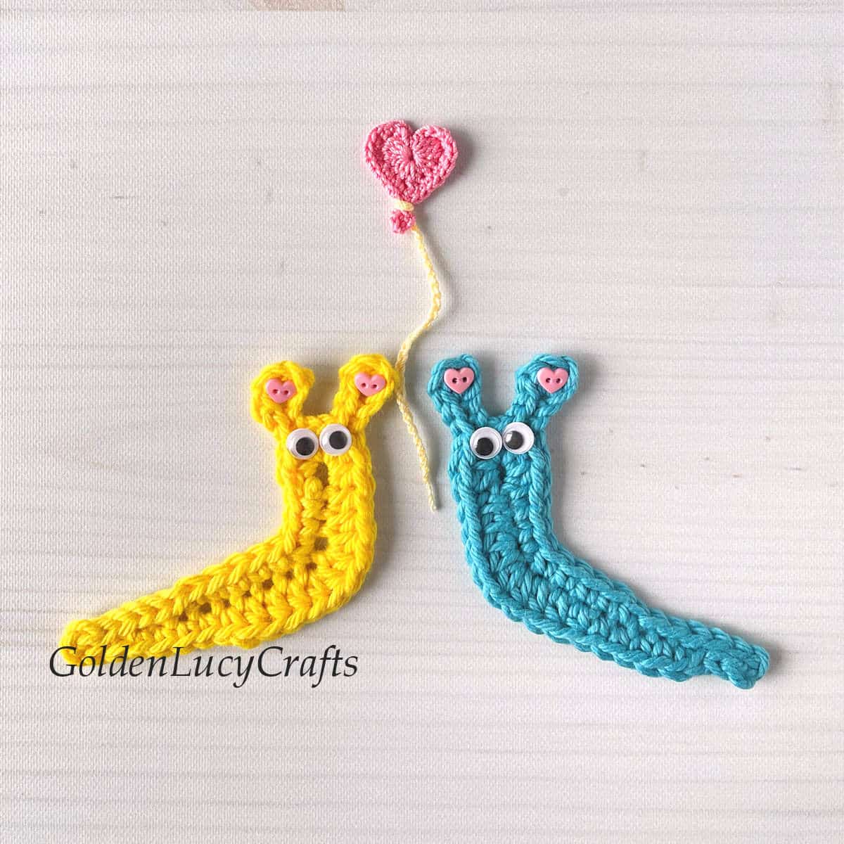 Two crocheted slugs and a heart balloon above them.