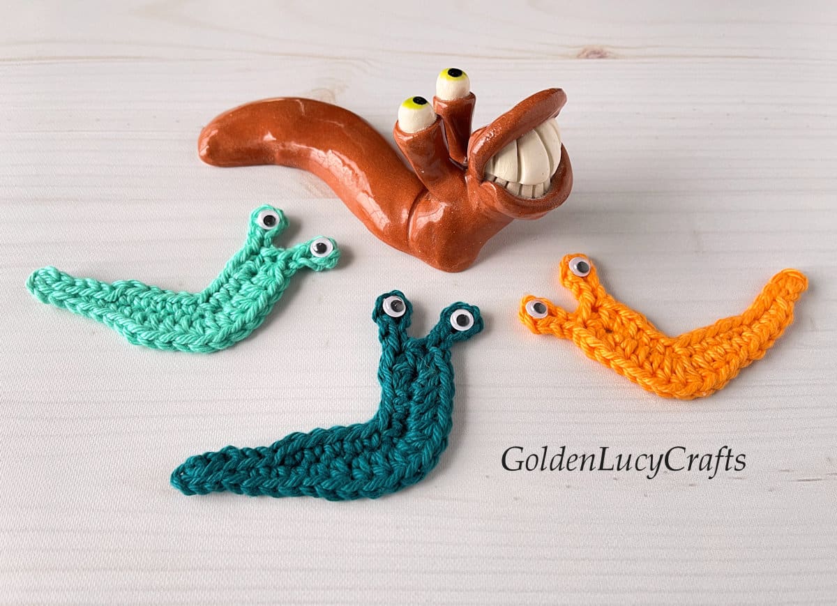 Three crocheted slug appliques and one ceramic slug.