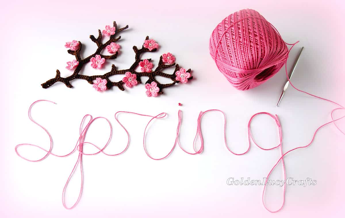 Crochet cherry tree branch, a skein of pink thread, crochet hook, word spring made from pink thread,