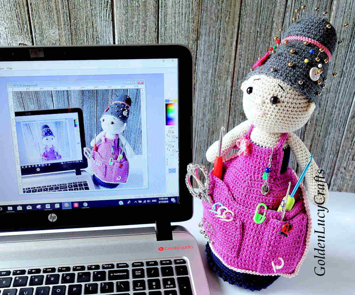 Crocheted crafter granny doll next to the computer.