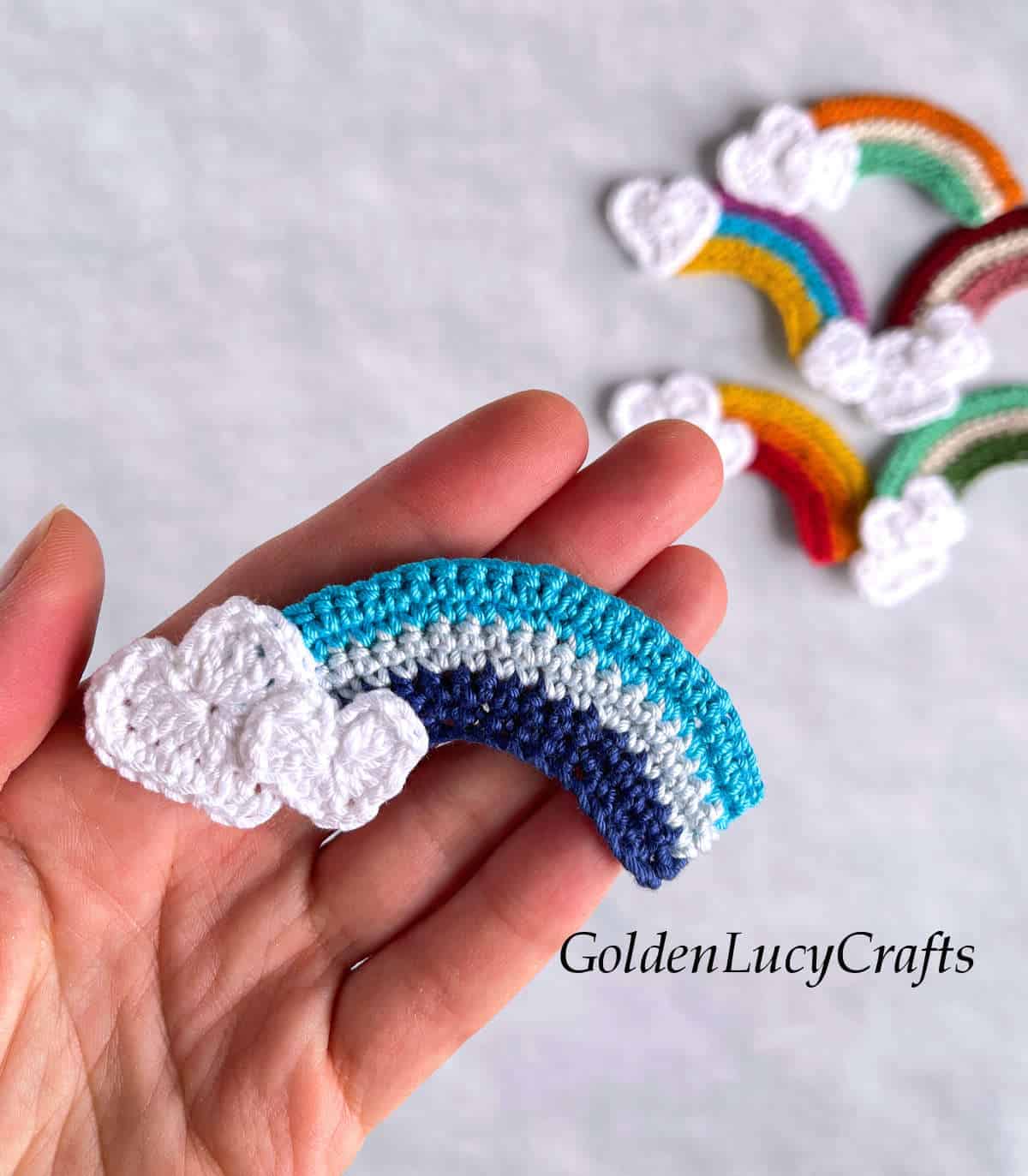 Crochet rainbow applique in the palm of a hand.