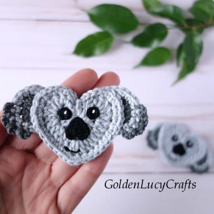 Crochet koala applique in the palm of a hand.