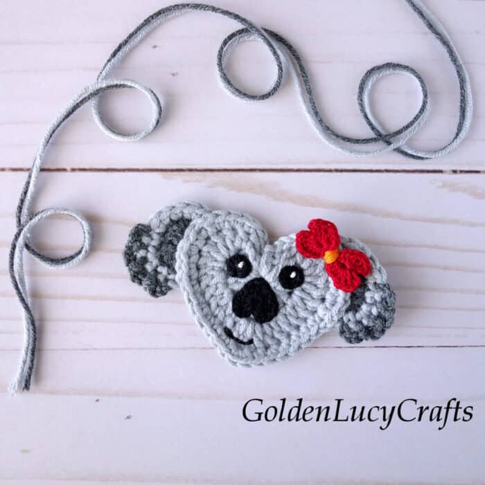 Crochet applique koala with a red bow.