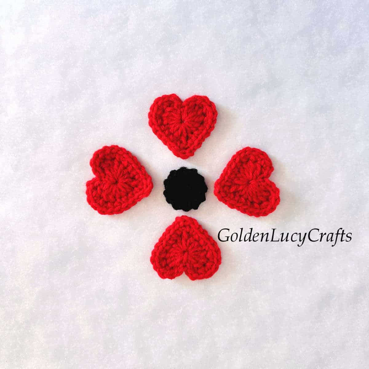 Elements of crochet poppy flower - four red heart and one black circle.