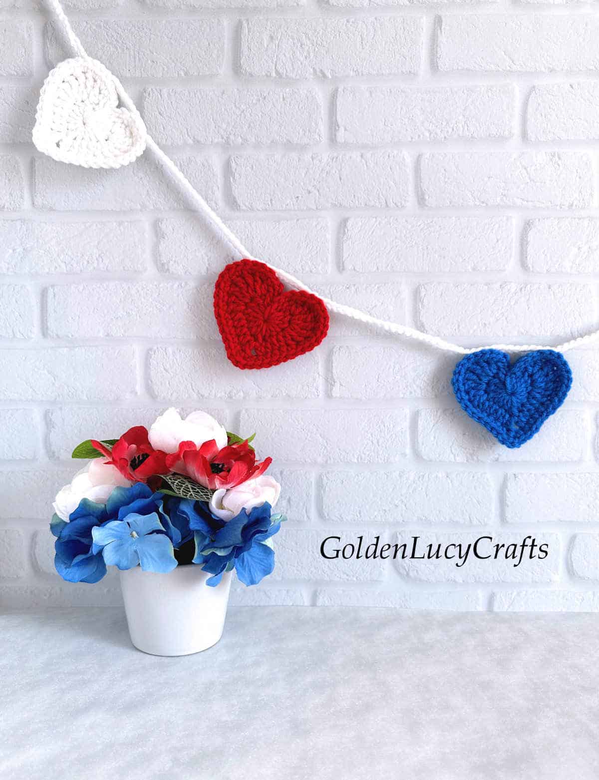 Crochet patriotic heart garland hanging on the wall.
