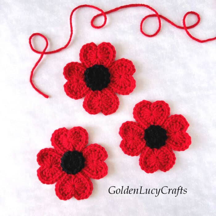 Three crocheted poppy flowers.