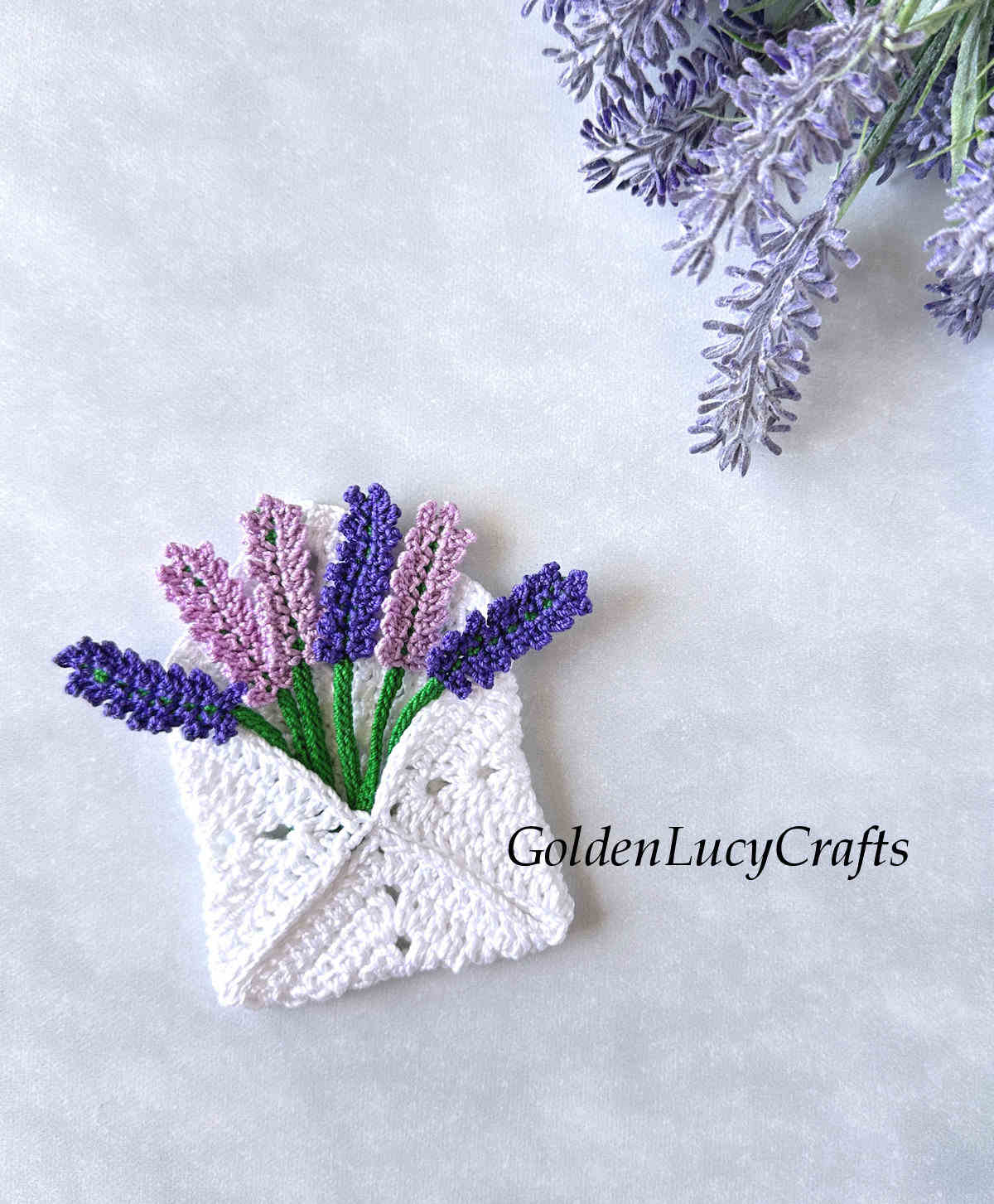 Crocheted white envelope with crocheted lavender flowers in it.