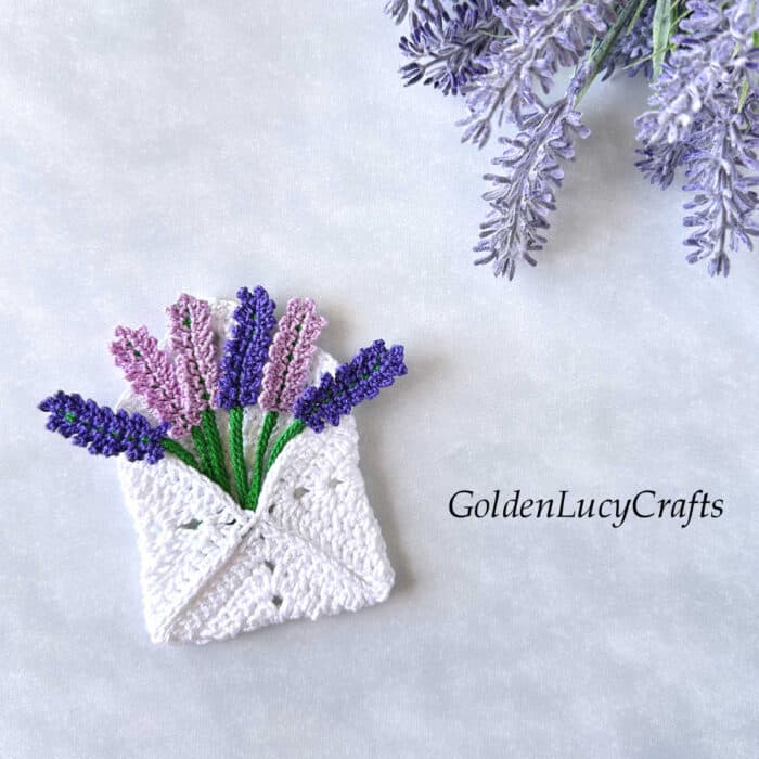 Crocheted envelope with crocheted lavender flowers in it.