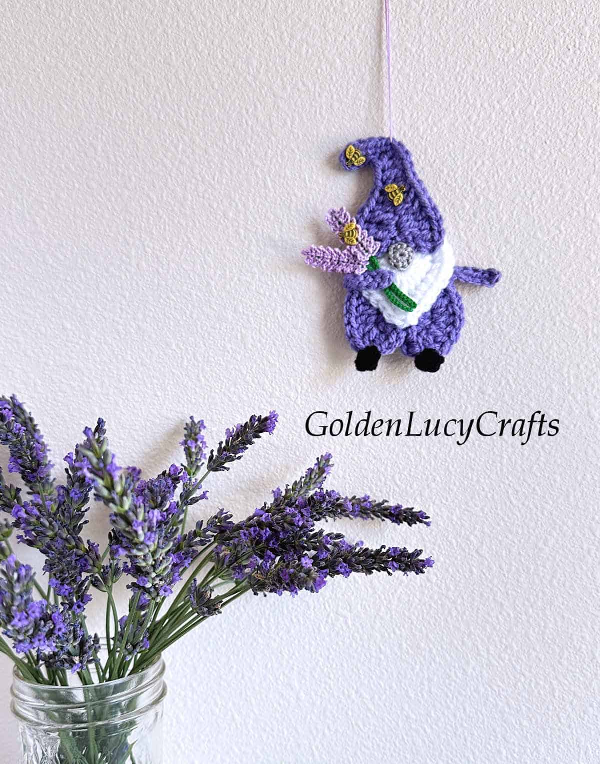 Crochet ornament lavender gnome hanging on the wall and lavender in the vase.