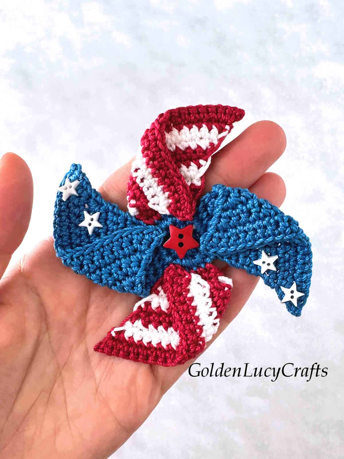 Crochet patriotic pinwheel in the palm of a hand.