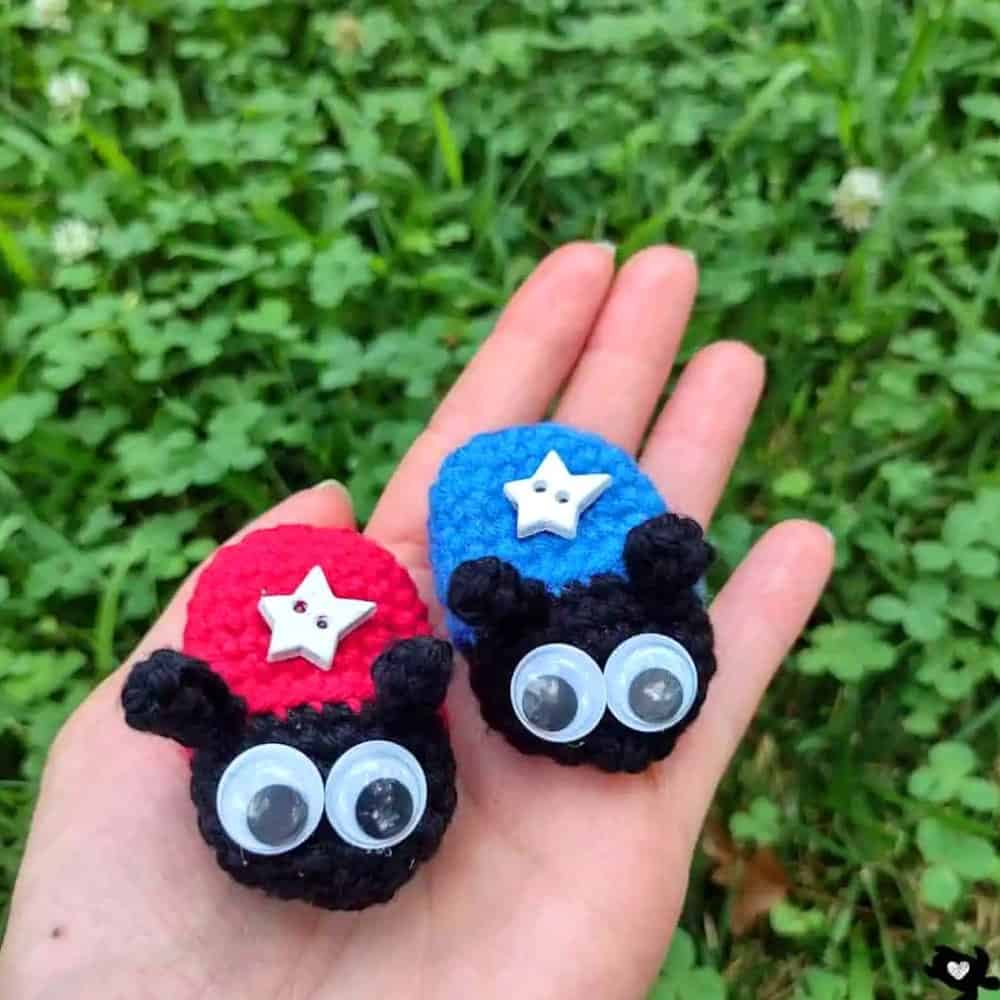 Two crocheted ladybugs in the palm of a hand.