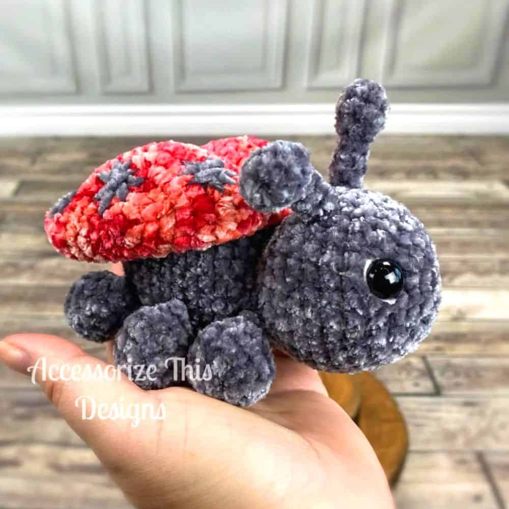 Crocheted ladybug amigurumi in the palm of a hand.