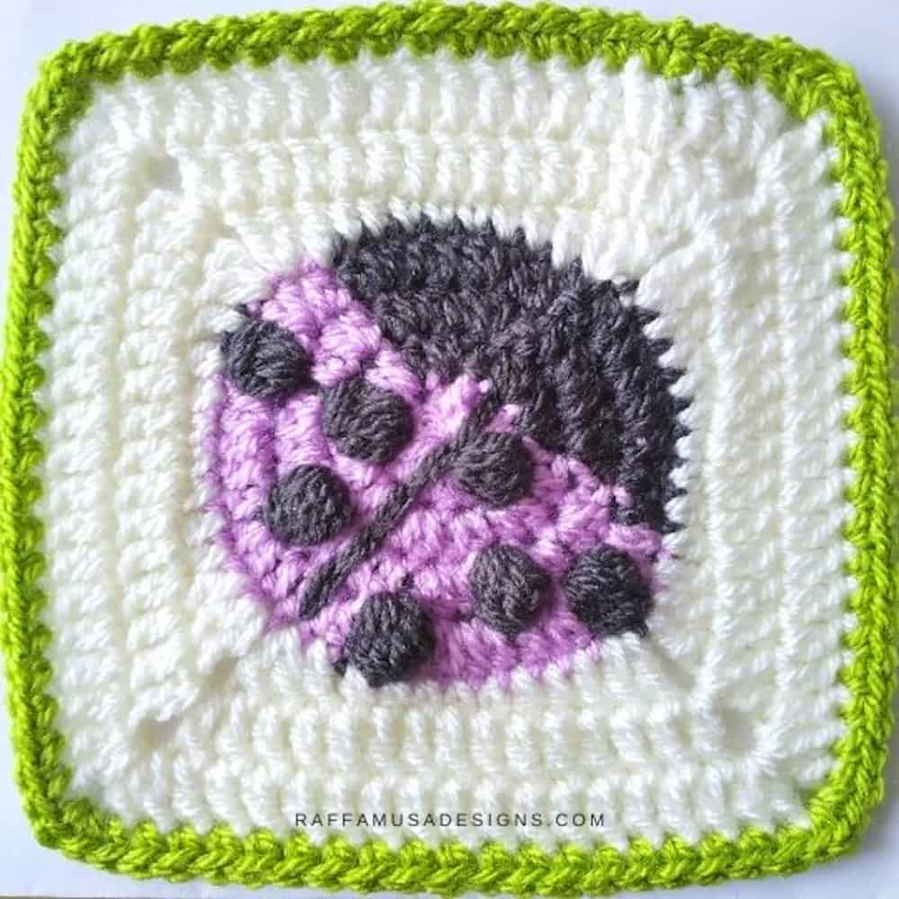 Crocheted square with purple ladybug in the center.