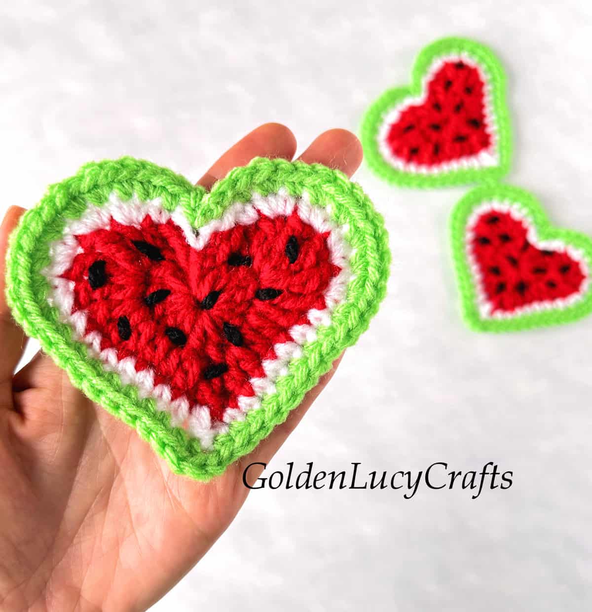 Crochet watermelon heart in the palm of a hand.