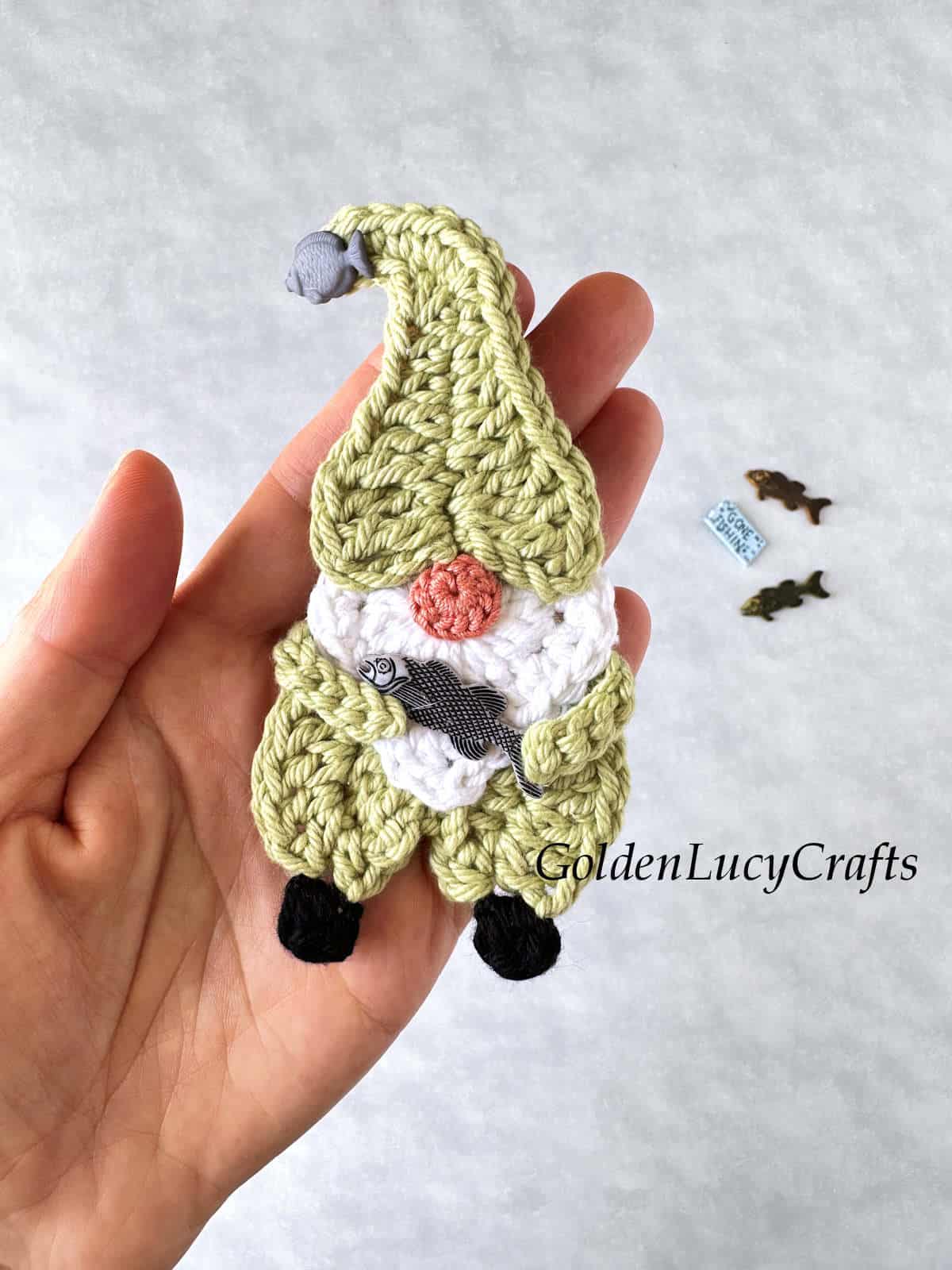 Crochet gnome holding fish in his hands.