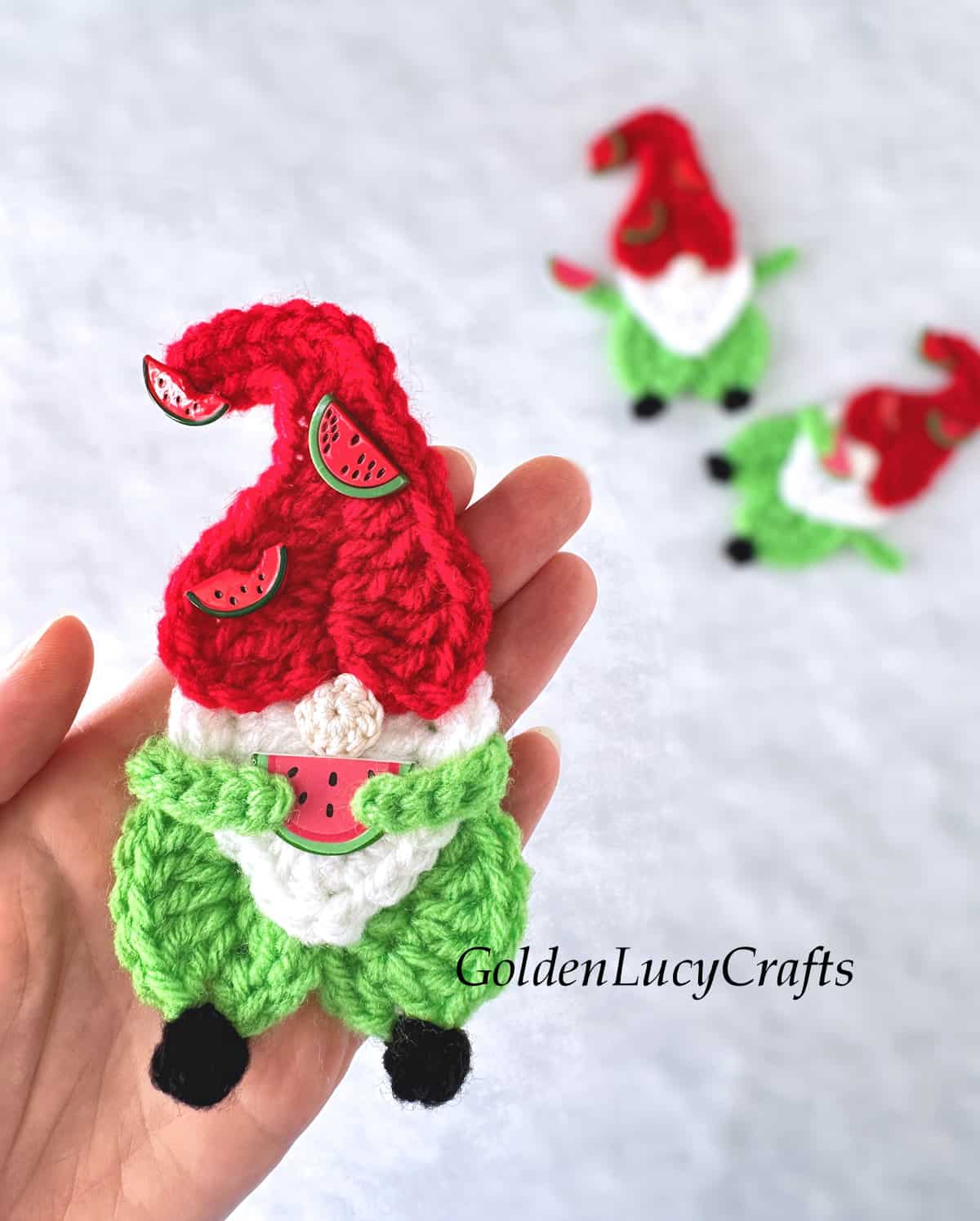 Crocheted gnome in the palm of a hand.