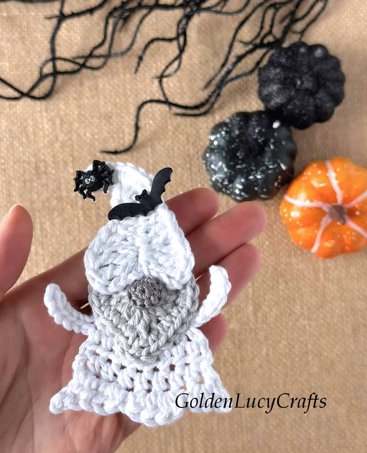 Crochet Halloween ghost gnome in the palm of a hand.