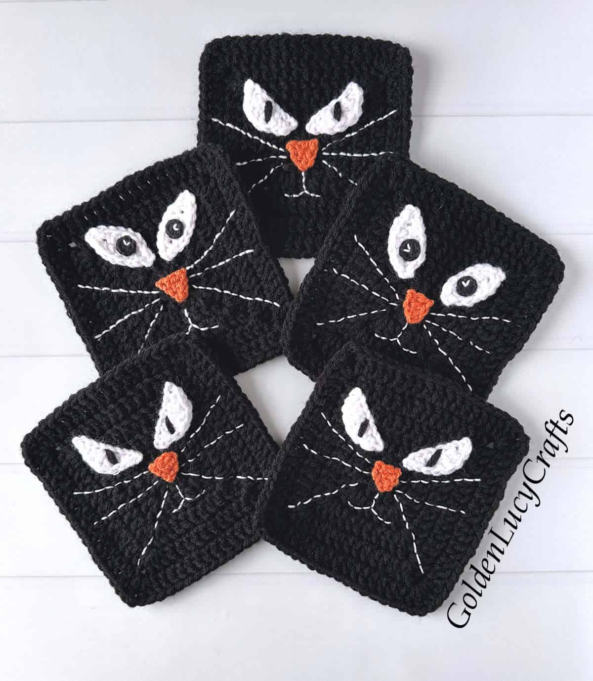 Five crocheted black squares with cat faces.