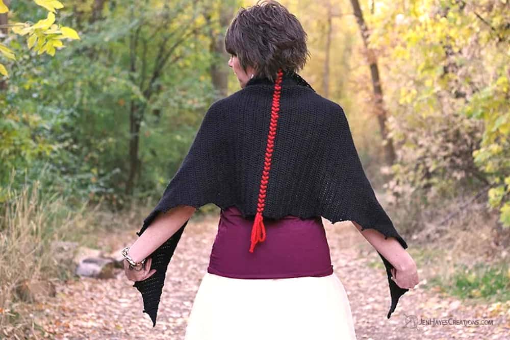 Model ia wearing crocheted black bat shawl.