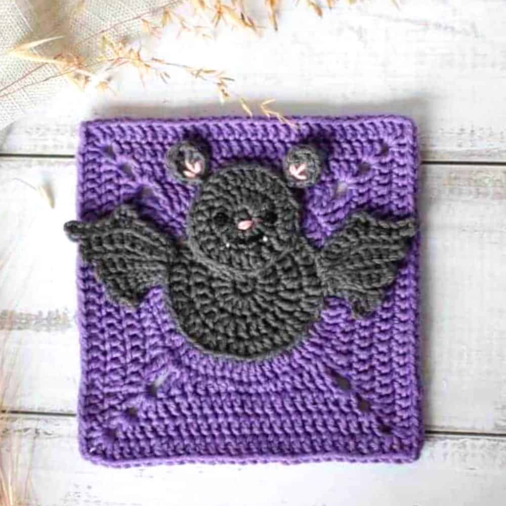 Crocheted purple square with black bat in the center.