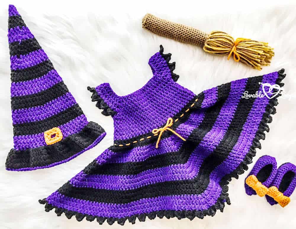Crocheted baby dress, hat, shoes and broom in purple and black colors.