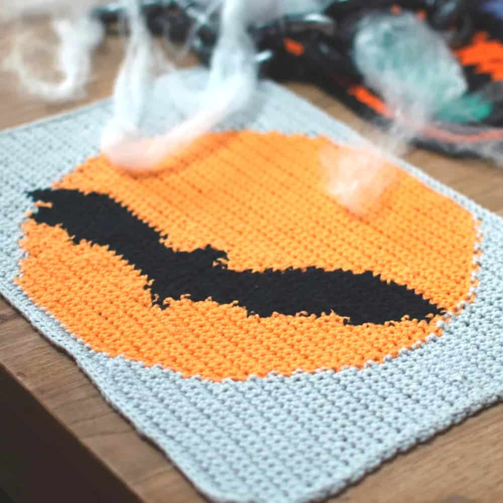 Crochet placemat with orange moon and black bat.
