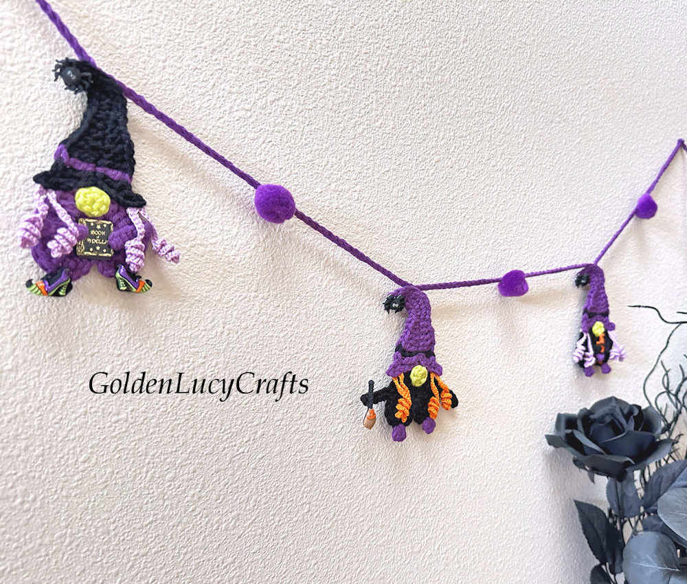 Crocheted witch garland hanging on the wall.