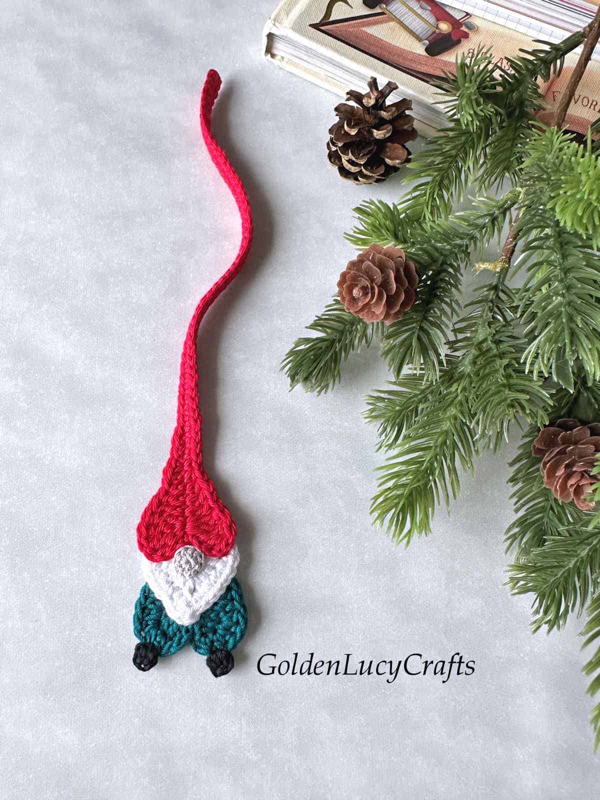 Crochet gnome made as bookmark next to the Christmas tree branch.