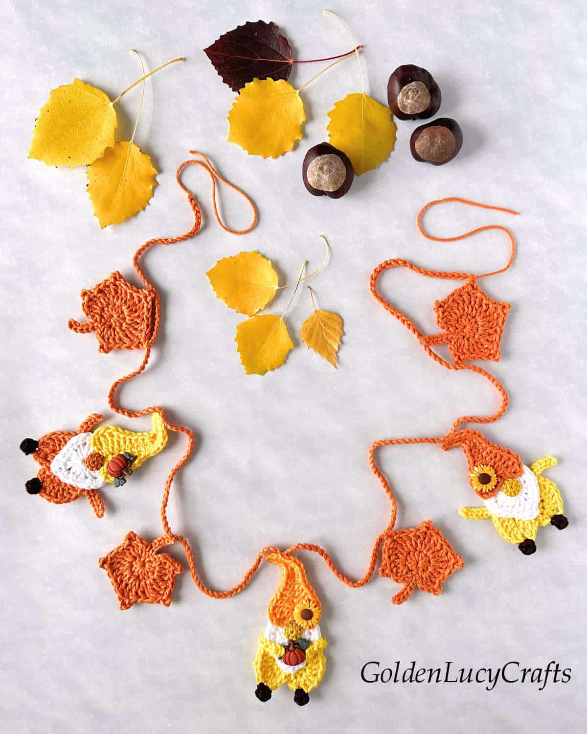 Crochet garland made of orange leaves and gnomes.