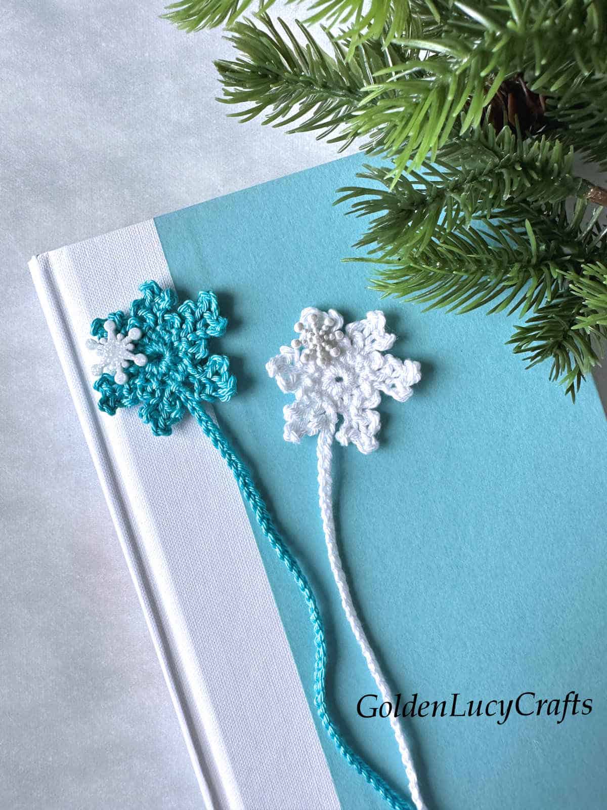 Two crochet snowflake bookmarks on the top of the book close up picture.