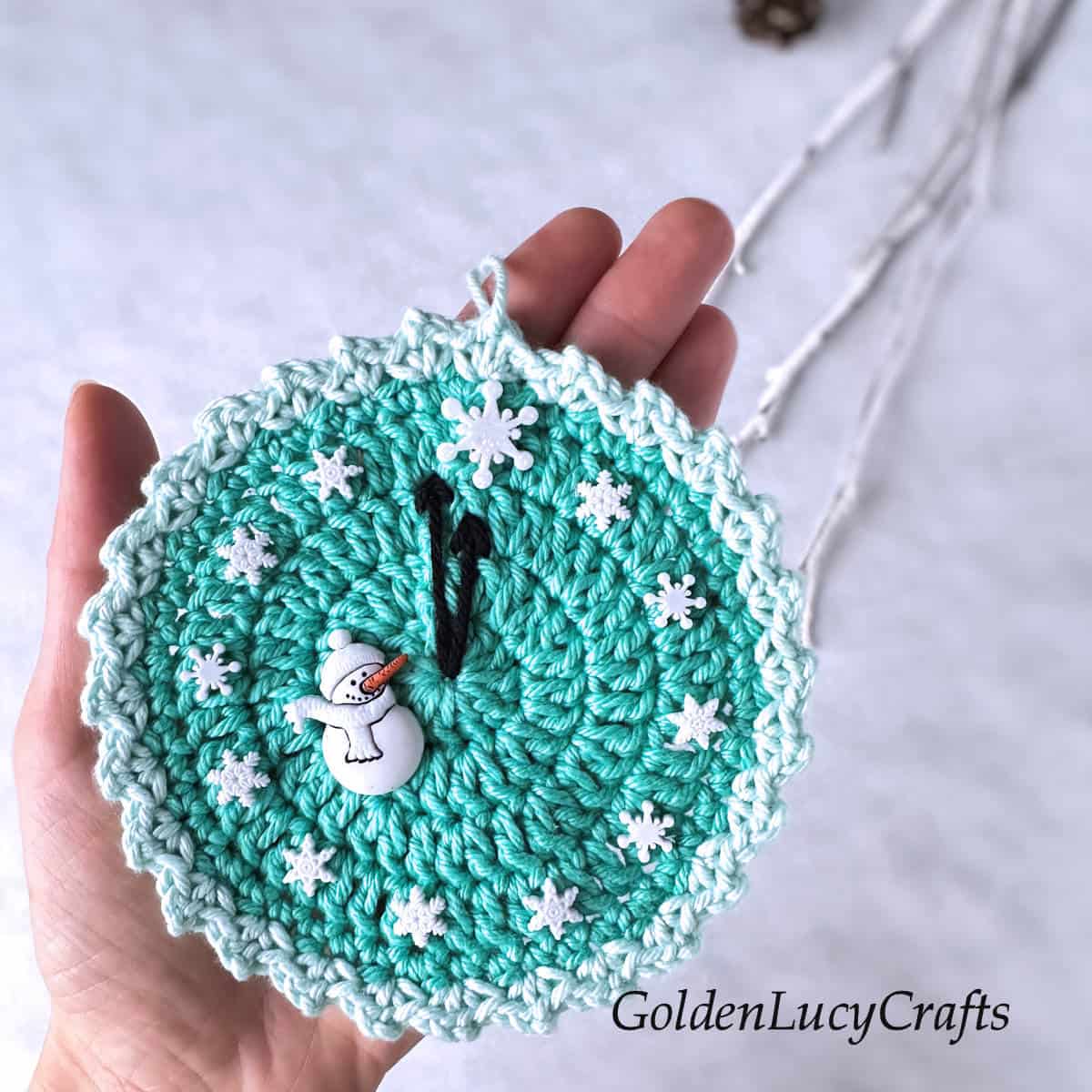 Crochet round ornament in the palm of a hand.