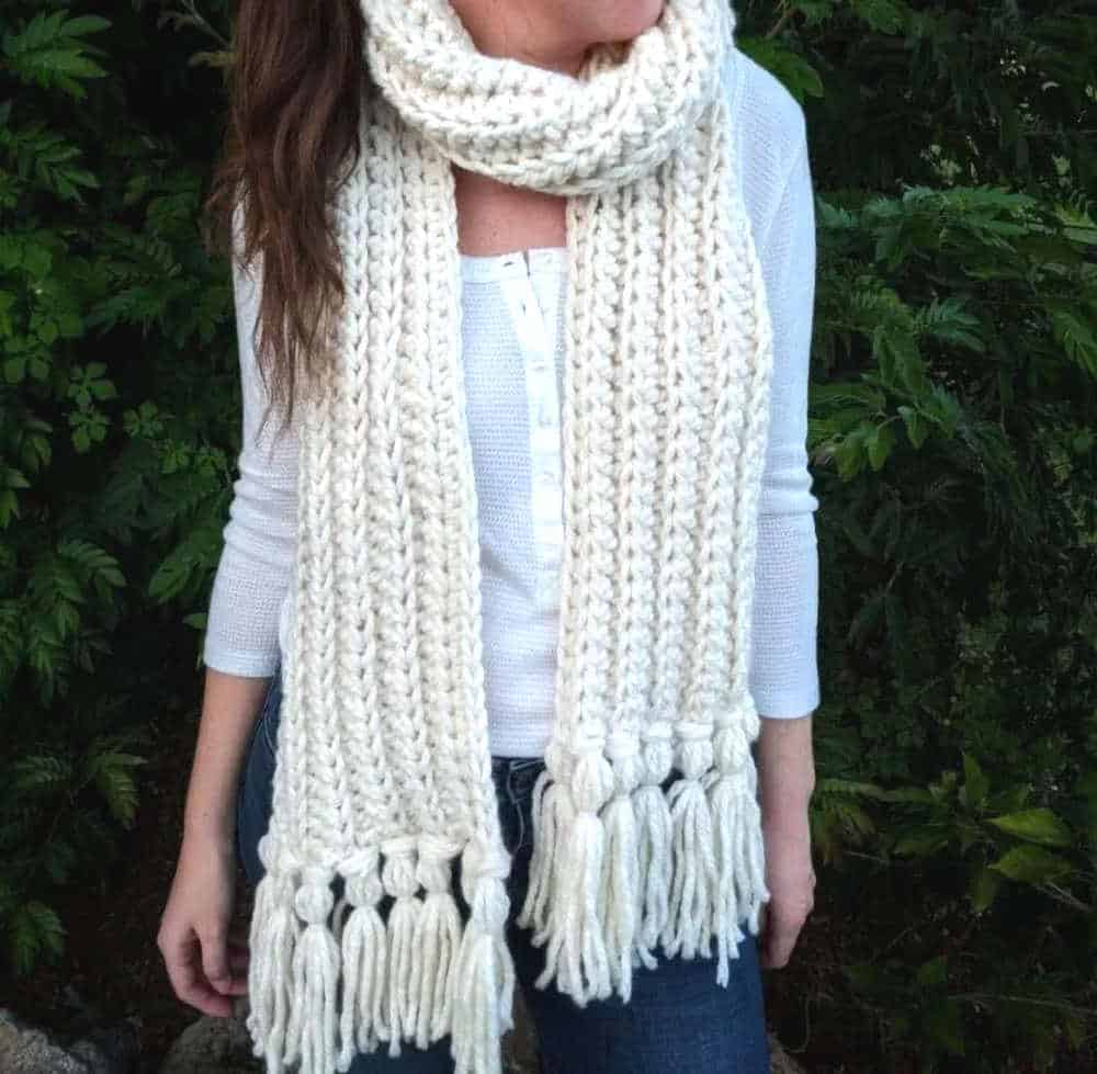 Model wearing crocheted white bulky scarf.