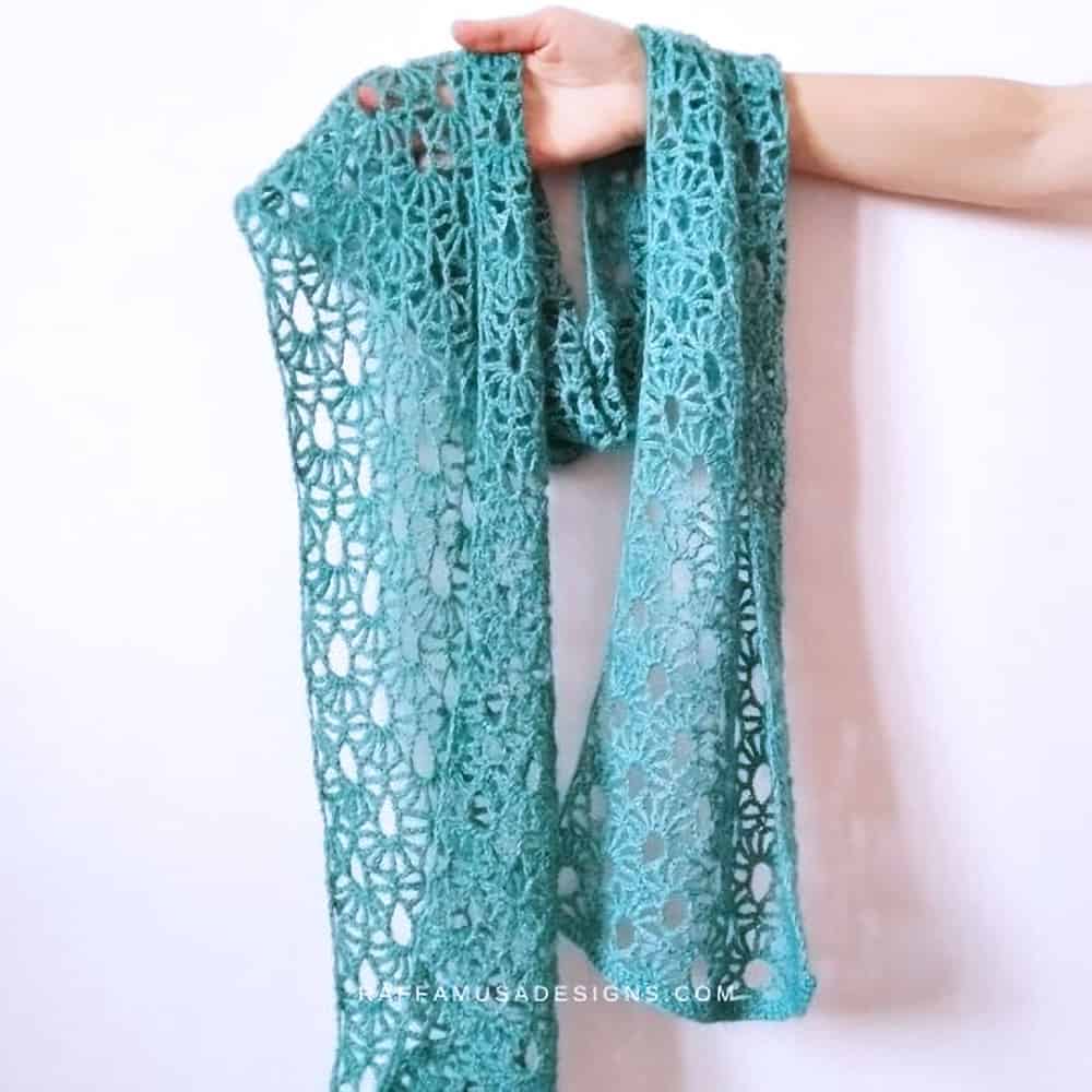 Crocheted lacy scarf held by hand.