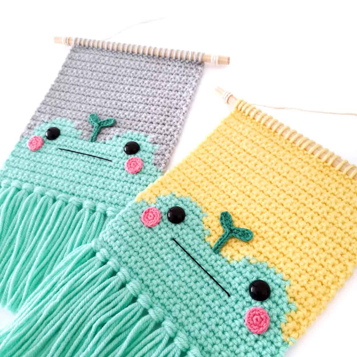 Two crocheted frog wall hangings.