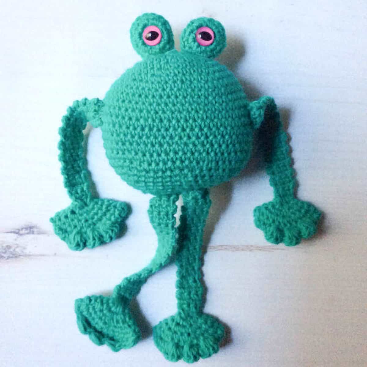 Crocheted frog with long arms and legs.
