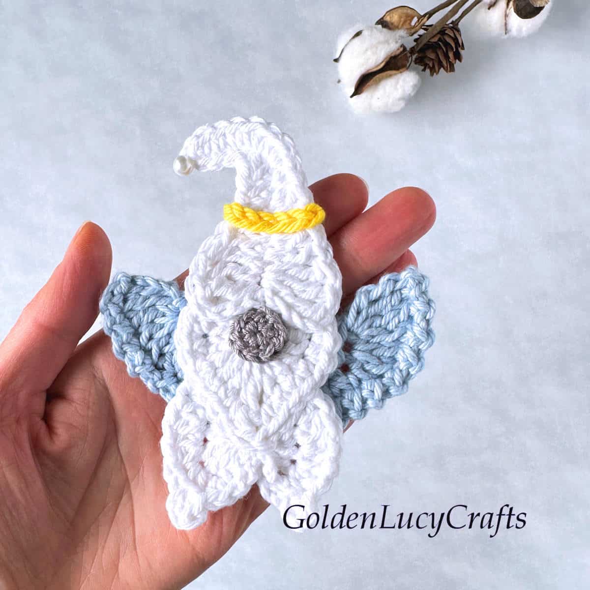 Crochet angel gnome in the palm of a hand.