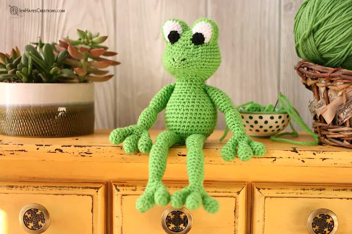 Crocheted green frog sitting on the drawer.