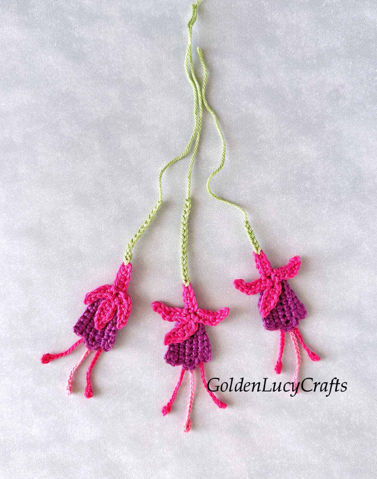 Three crocheted fuchsia flowers.