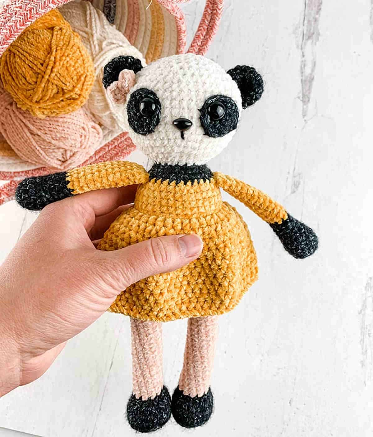 Crochet panda toy in yellow dress.