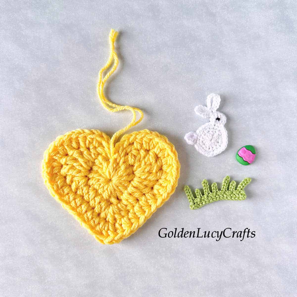Crochet yellow heart, white bunny, grass and Easter egg craft button.