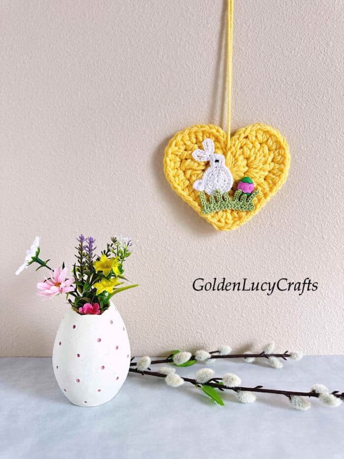 Crochet Easter heart ornament hanging on the wall.