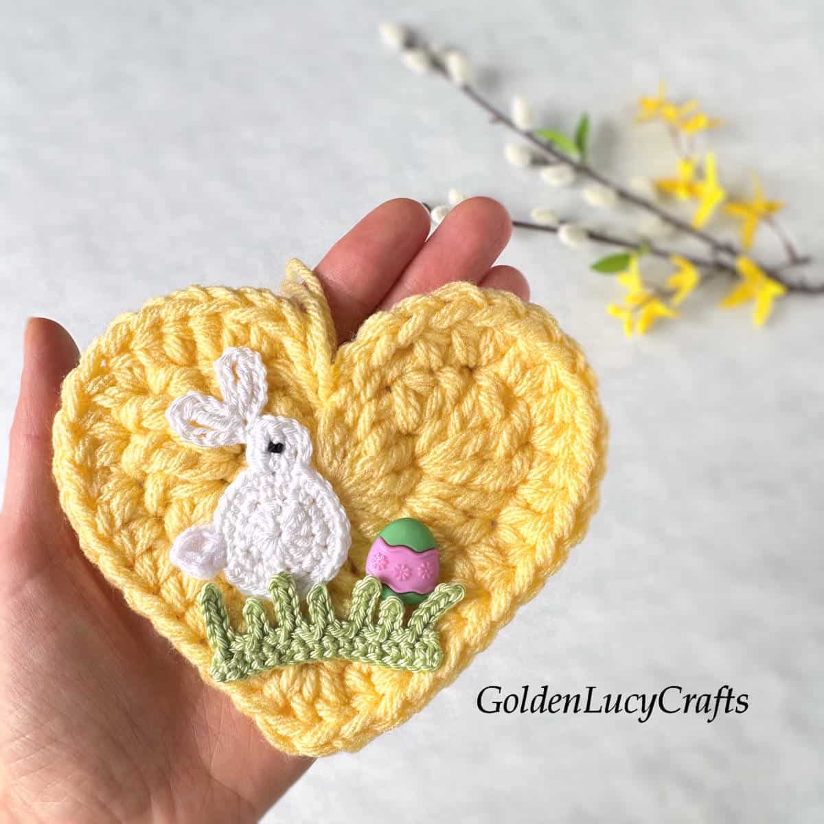 Crochet Easter heart in the palm of a hand.