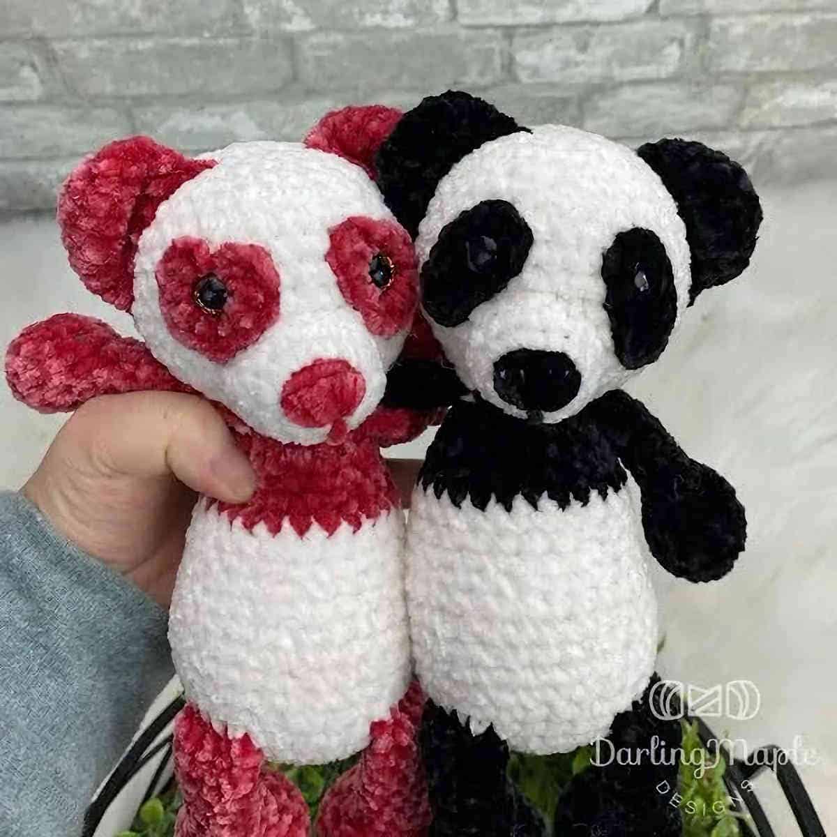 Two crocheted panda toys held by hand.