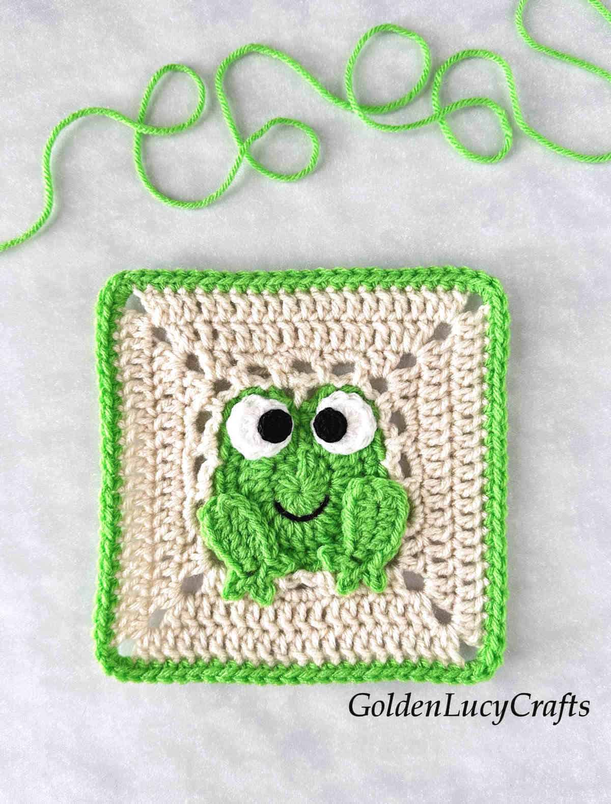 Crochet square with frog in the middle.