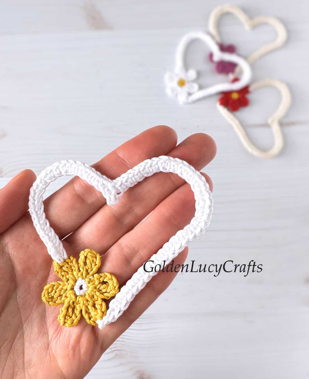 Crocheted heart in the palm of a hand.