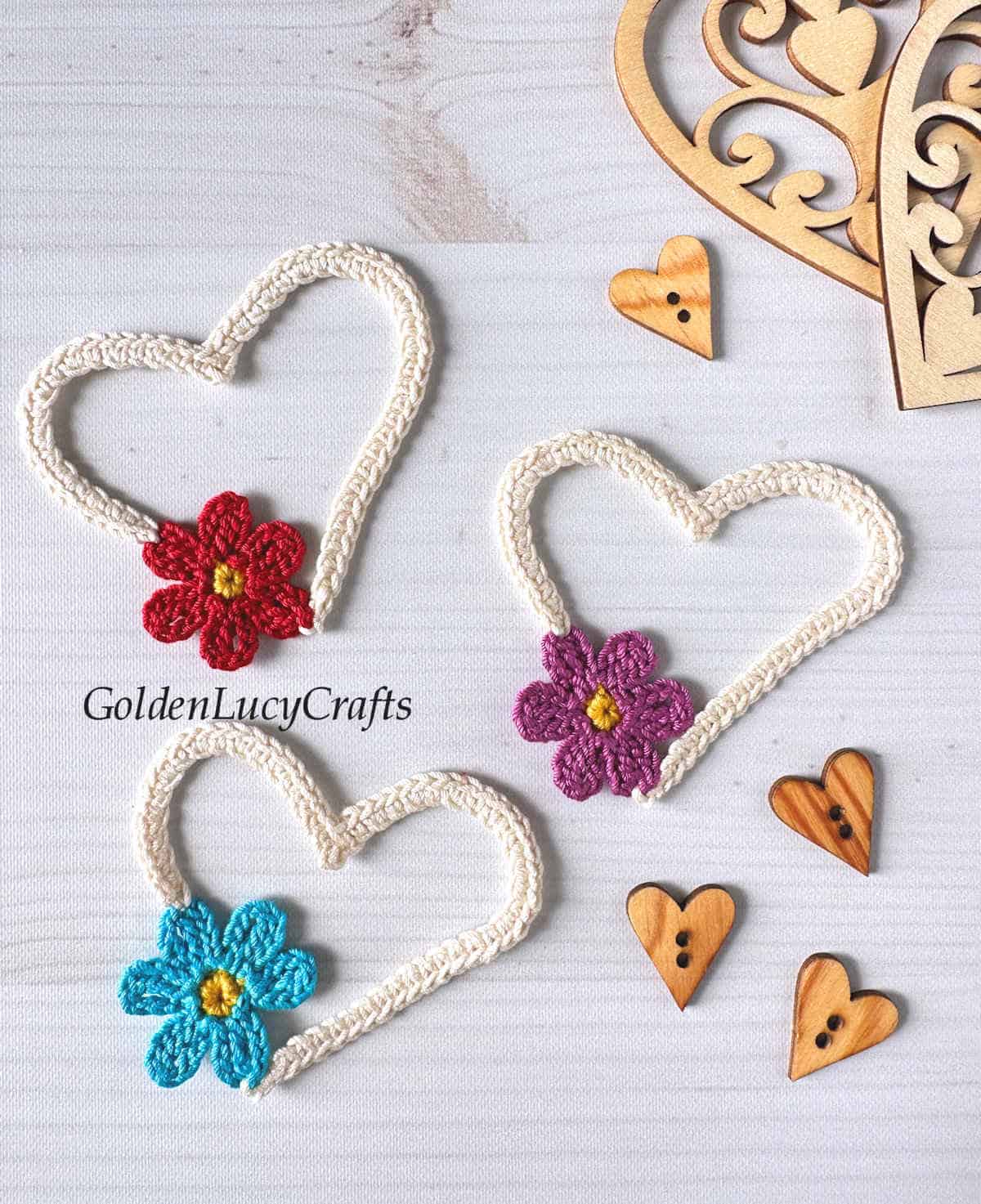 Three crocheted hearts with flowers incorporated in them.