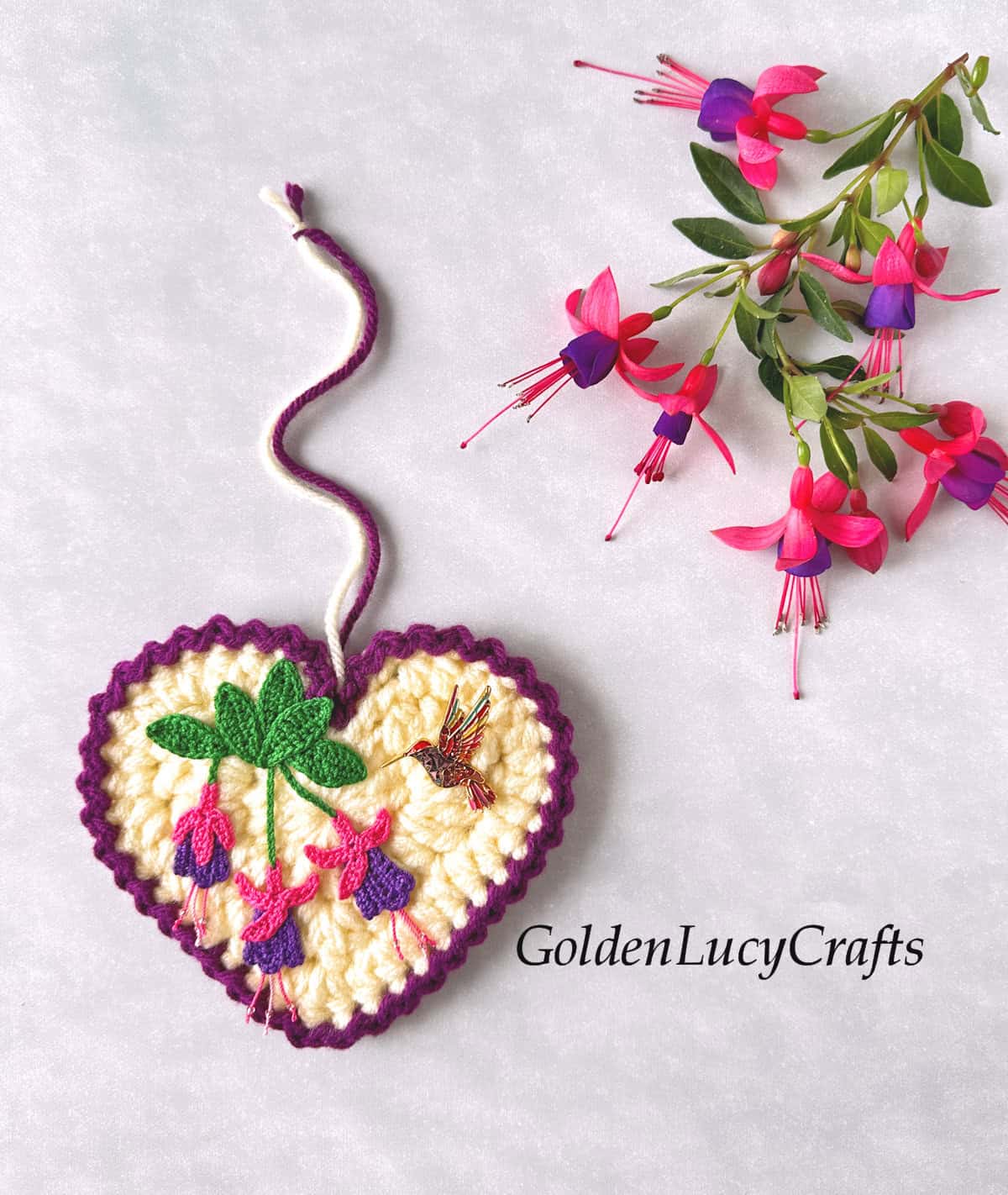 Crocheted heart with fuchsia and hummingbird on it.