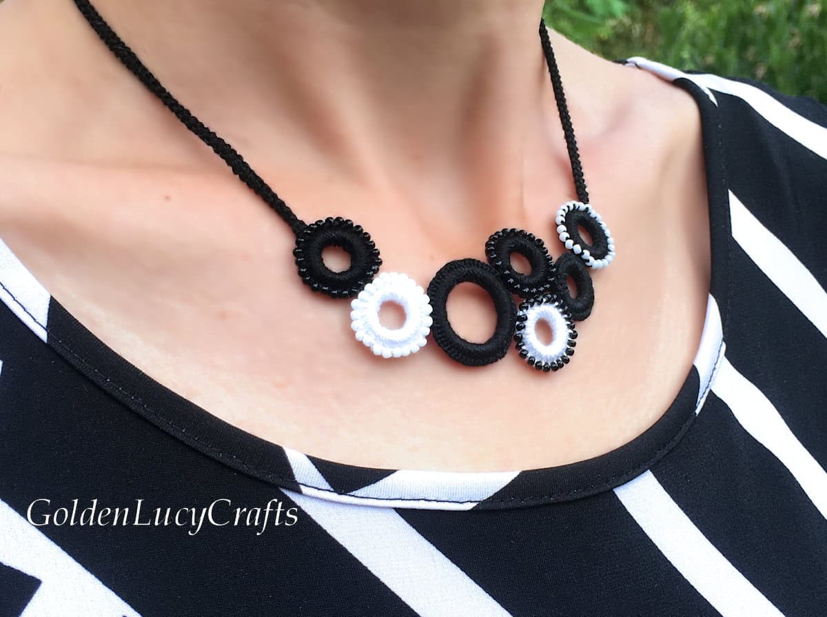 Model wearing black and white crocheted necklace, close-up picture.