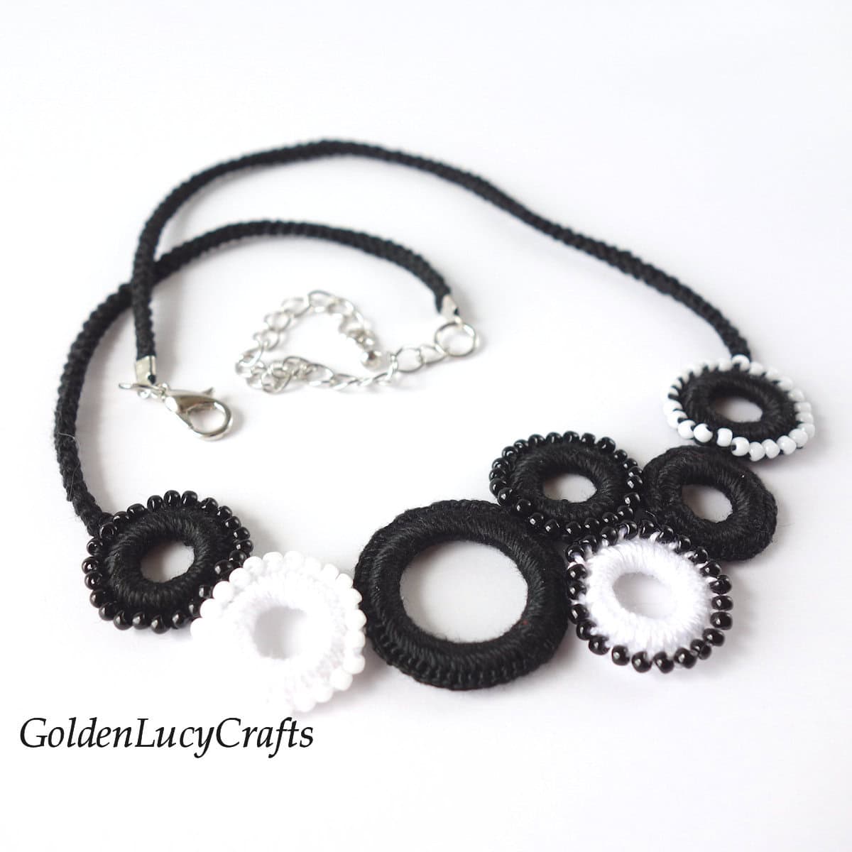 Crocheted necklace made of small black and white rings and embellished with seed beads.